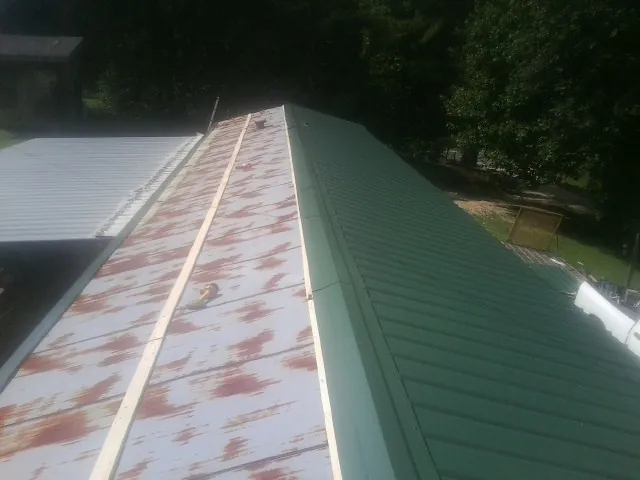 Old rusted panels beside newly installed green metal roofing — Wind Damage Roof Repair by Roofing Brothers in Macedonia