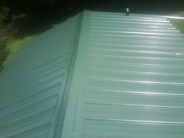 New green metal panels meeting at the ridge of a roof — Flat Roof Repair work by our crew in Macedonia