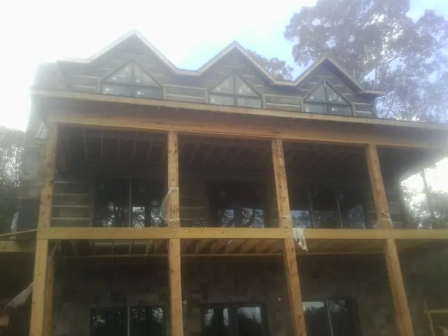 Dormers and porch framing on a large log home under construction — Roof Coating work by our crew in Macedonia