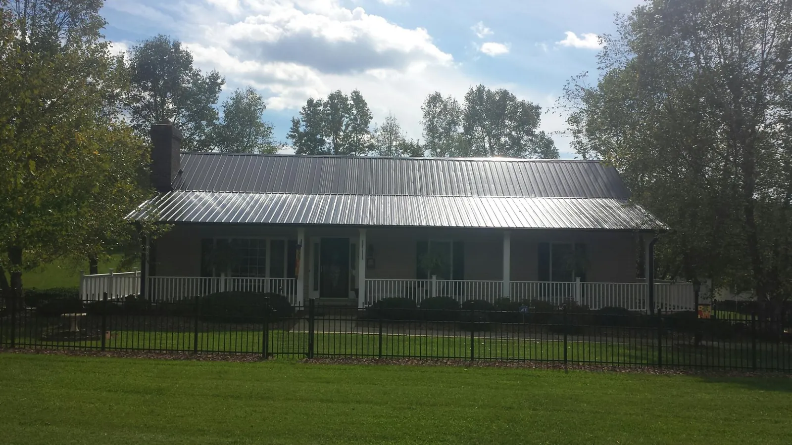 Gray metal roof on a brick ranch with a full width front porch — Gutter Guard Installation work by our crew in Macedonia