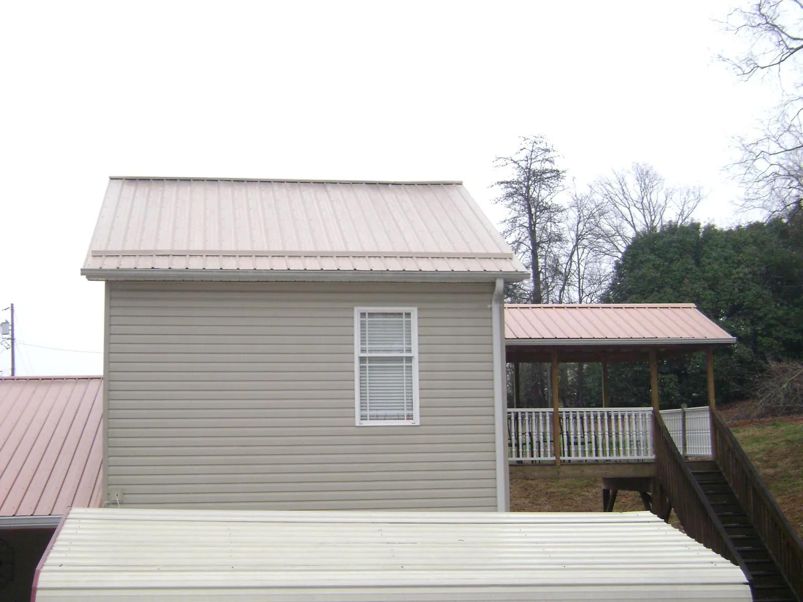 Tan metal roofs on a two story addition and attached porch, from a Roof Replacement job in Macedonia